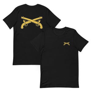 May include: A black short-sleeve t-shirt featuring a large yellow graphic of two crossed antique pistols on the back and a smaller version of the same crossed pistols graphic printed on the front left chest area of the garment.