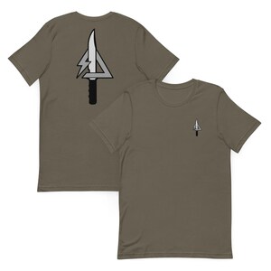 May include: Two olive green t-shirts. One shirt has a small graphic on the front and a larger graphic on the back. The graphics are a white and gray triangle with a knife and lightning bolt design.
