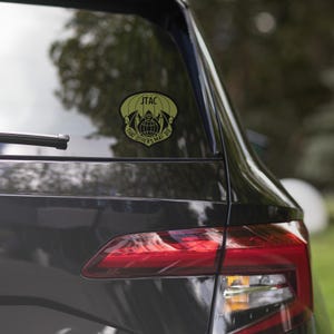 May include: A yellow and black car sticker with a parachute and the text "JTAC That Others May Live".