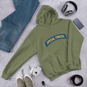 Peut inclure: Un sweat-shirt à capuche vert avec le texte "SPECIAL FORCES" en lettres jaunes sur un patch bleu.