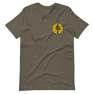 May include: Olive green t-shirt featuring a black and yellow circular emblem on the left chest. The emblem has a yellow background with a black lightning bolt design inside a black arrow.