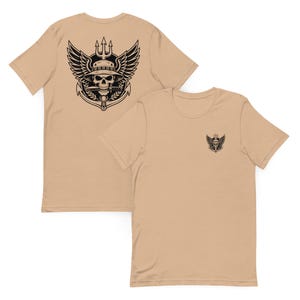 Peut inclure: Deux t-shirts beiges. L'un présente un grand motif noir au dos d'un crâne portant un chapeau, des ailes et un trident. L'autre a une version plus petite du motif sur le devant.