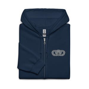 Könnte beinhalten: Marineblauer Kapuzenpullover mit Reißverschluss und silbernem Emblem auf der Brust. Das Emblem zeigt einen Globus, umgeben von einem Lorbeerkranz. Der Kapuzenpullover hat einen durchgehenden Reißverschluss und eine Kapuze.