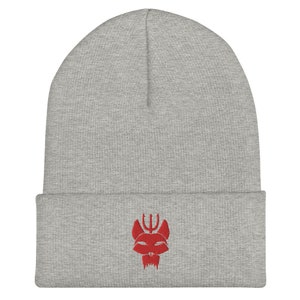 Puede incluir: Gorro gris con un logotipo bordado en rojo de una cabeza de animal estilizada con un tridente en la parte superior.