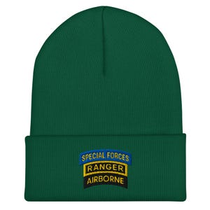 May include: A dark green beanie with a folded brim. The beanie features an embroidered patch with the words "SPECIAL FORCES RANGER AIRBORNE" in blue, yellow, and black. This hat is a military-themed accessory.