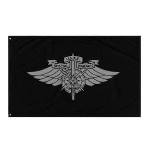 May include: Black flag featuring a silver emblem of the U.S. Air Force Special Warfare. The emblem includes wings, a sword, a compass rose, and the text "U.S.A.F. SPECIAL WARFARE" on a banner. The flag is rectangular with grommets.