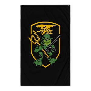 May include: Black flag featuring a cartoon frog in a green hat and flippers, holding a trident and a rifle. The frog is inside a yellow shield with a yellow emblem of a bird and trident.