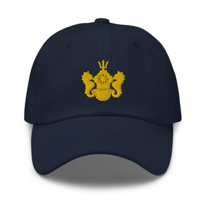 May include: A navy blue baseball cap with a gold embroidered emblem featuring a diving helmet, trident, and seahorses.