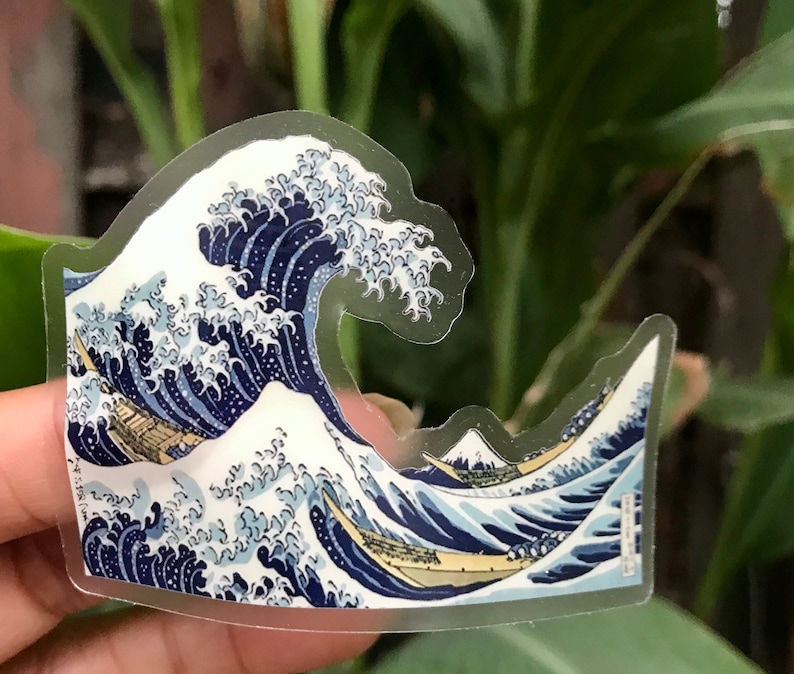 Pu&ograve; includere: Un adesivo trasparente con un'immagine blu e bianca di un'onda grande con una barca in primo piano. L'onda &egrave; un design d'arte giapponese tradizionale.