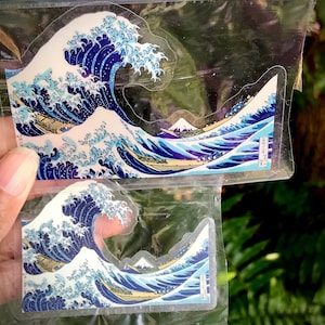 Pu&ograve; includere: Due fogli di plastica trasparente con un disegno di onda giapponese blu e bianco stampato su di essi. Il disegno dell'onda &egrave; un'opera d'arte giapponese tradizionale.