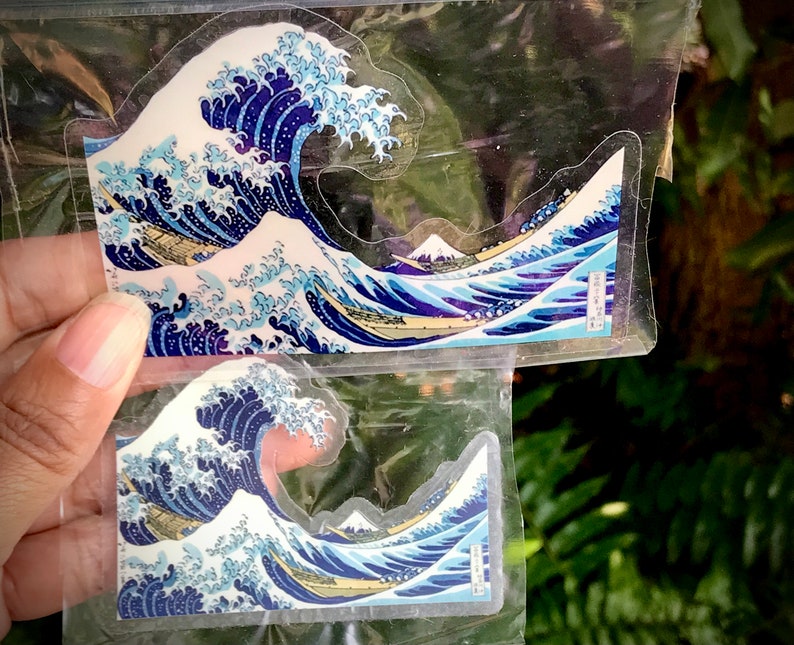 Pu&ograve; includere: Due fogli di plastica trasparente con un disegno di onda giapponese blu e bianco stampato su di essi. Il disegno dell'onda &egrave; un'opera d'arte giapponese tradizionale.