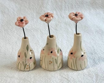Jarrón de cerámica miniatura hecho a mano con flores silvestres rosas.