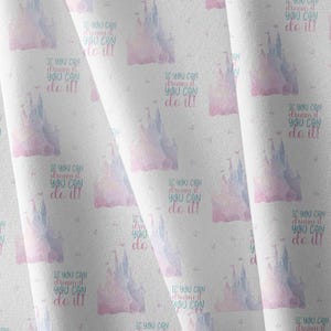 May include: A white fabric featuring a repeating pattern of watercolor-style pink and blue castles. Each castle is accompanied by the text "If you can dream it you can do it!" printed in a mix of blue and pink script and block lettering.