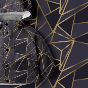 May include: A dark navy blue hooded jacket featuring a geometric pattern of thin gold lines. The jacket has a front placket with black snap buttons, a hood, and two front pockets. The same gold and navy geometric pattern is visible behind it.