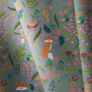 May include: A light blue fabric featuring a repeating pattern of orange foxes, small yellow and green birds, and various colourful flowers and green leaves. The design includes stylised floral elements in shades of pink, yellow, and green.