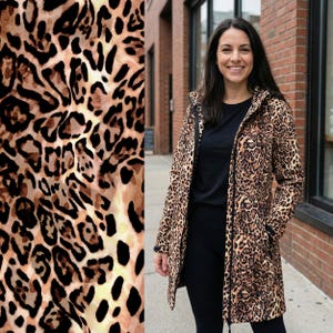 May include: A long-sleeved jacket featuring a brown, tan, and black leopard print pattern. The jacket has a hood, a full-length front zipper, and two side pockets. It is worn over a solid black shirt and black leggings, creating a cohesive look.