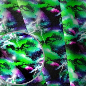 May include: A fabric sheet featuring a vibrant space-themed pattern with bright green and purple nebula clouds, scattered white stars, and jagged white lightning bolts across a deep black background, shown with a circular magnifying overlay.