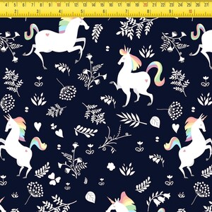 May include: A dark navy blue fabric featuring a repeating pattern of white unicorns with rainbow-colored manes and tails, interspersed with white botanical illustrations of leaves, flowers, and small hearts, measured by a yellow 12-inch ruler.