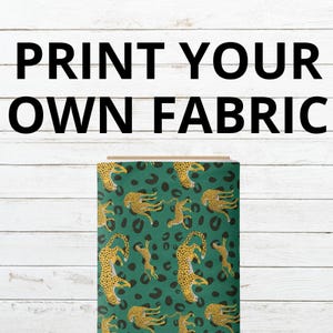 Może przedstawiać: Belka materiału z powtarzającym się wzorem żółtych i czarnych lampartów na ciemnozielonym tle. Tekst PRINT YOUR OWN FABRIC jest wyświetlany dużymi czarnymi wielkimi literami nad belką materiału na białej drewnianej powierzchni.