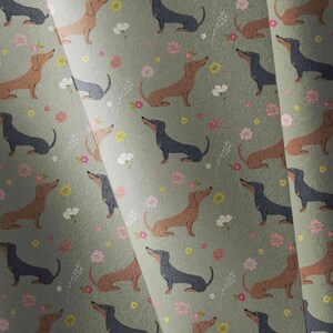 May include: A seamless pattern featuring brown and black dachshund dogs on a green background with pink, yellow and white flowers.
