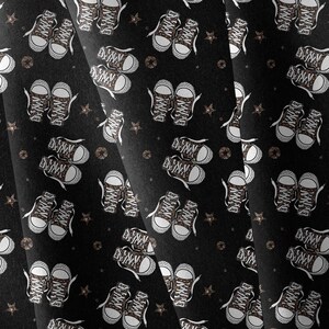 May include: A black fabric featuring a repeating pattern of brown leopard print sneakers with white laces and rubber toe caps, interspersed with small brown stars. The design is printed across the textile, showing multiple pairs of shoes.