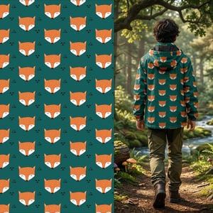 May include: A hooded jacket featuring a repeating pattern of orange and white fox faces on a dark teal background. The jacket has long sleeves, a hood, and a zipper closure, worn with olive green pants while standing on a dirt path.
