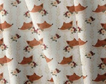 May include: A fabric featuring a repeating pattern of orange fox heads with closed eyes, each adorned with a cluster of small cream and dark red flowers, set against a light cream background with vertical rows of pale beige leaf silhouettes.