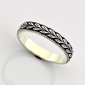 Könnte beinhalten: Ein silberner Ring mit einem detaillierten Blattmuster. Der Ring hat ein Band aus Blättern und einen Perlenrand. Der Ring hat die Größe 54 und ist aus Sterlingsilber. Ein schönes Schmuckstück.