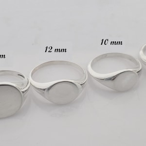 Könnte beinhalten: Vier silberne Siegelringe in verschiedenen Größen, jeweils mit einer flachen, ovalen Oberfläche. Die Ringe sind mit ihren Durchmesser beschriftet: 15 mm, 12 mm, 10 mm und 8 mm. Die Ringe werden auf hellem Hintergrund gezeigt.