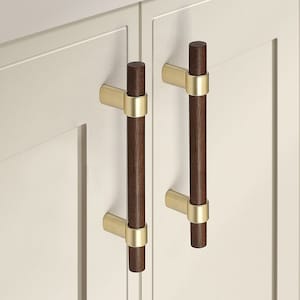 Op de afbeelding: Twee kastgrepen met een donkerhouten afwerking en gouden accenten. De grepen zijn gemonteerd op witte kastdeuren.