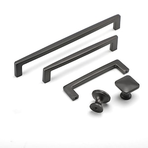 May include: A set of five black cabinet hardware pulls and knobs. The set includes three different sizes of bar pulls and one knob in a round shape and one in a square shape.