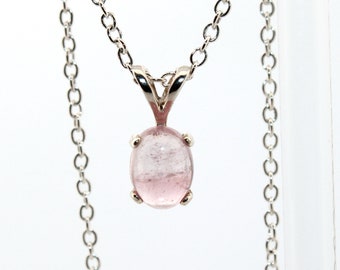 May include: A silver chain necklace with a pink gemstone pendant. The gemstone is oval shaped and has a smooth, polished finish.