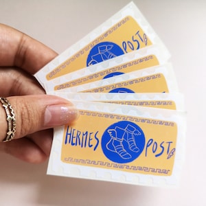 May include: A stack of five stickers with a yellow background and a blue circle containing a winged sandal. The text "Hermes Post" is written in black and white on the sticker.