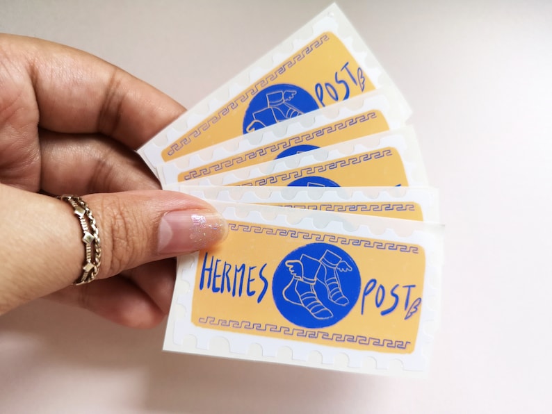 May include: A stack of five stickers with a yellow background and a blue circle containing a winged sandal. The text "Hermes Post" is written in black and white on the sticker.