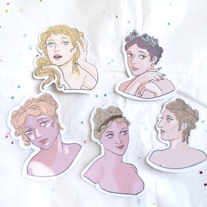 Puede incluir: Conjunto de cinco pegatinas con ilustraciones de mujeres con peinados y atuendos cl&aacute;sicos. Las pegatinas tienen una paleta de colores suaves de rosa, beige y dorado. Cada pegatina representa una pose y expresi&oacute;n diferente, con detalles como coronas florales y cabello suelto.