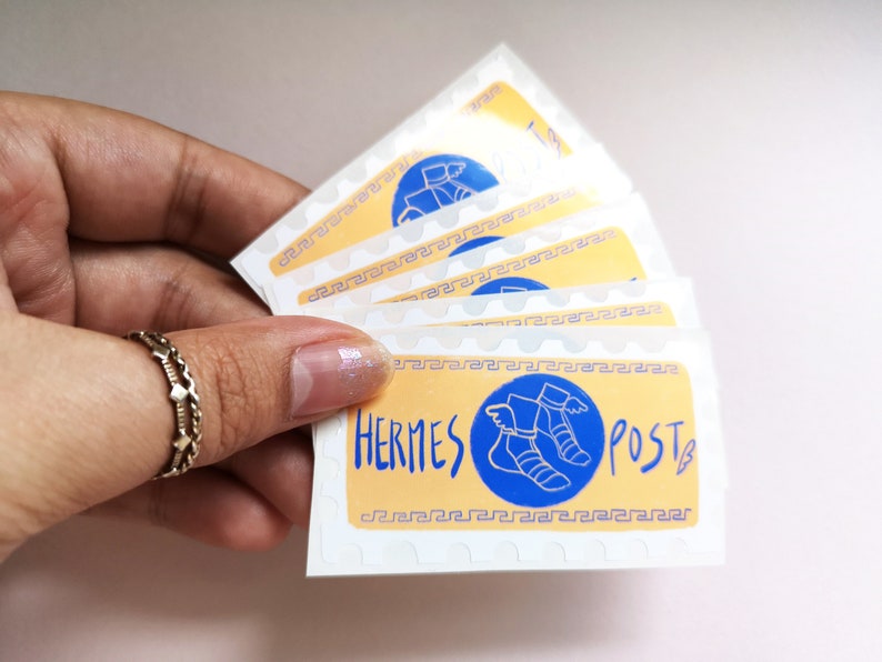 May include: A set of five stickers featuring a yellow background with a blue circle containing a winged sandal. The text "HERMES POST" is written in blue lettering.