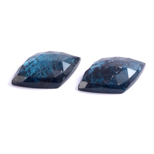 May include: Two dark blue, faceted, gemstone cabochons with a cloudy, speckled appearance.
