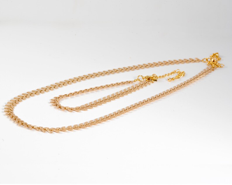 Op de afbeelding: Een gouden ketting met een delicaat, gelaagd ontwerp. De ketting is gemaakt van kleine, puntige schakels die lijken op pijlpunten. De ketting is perfect om te combineren met andere sieraden.