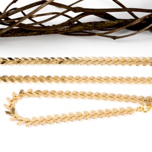 Op de afbeelding: Twee gouden kettinghalskettingen met een chevron-patroon. De kortere ketting is een armband.