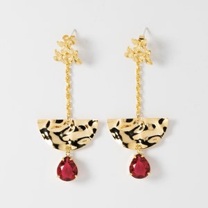 May include: Gold earrings with a teardrop-shaped red gemstone, a half-circle design, and a cluster of small gold flowers.