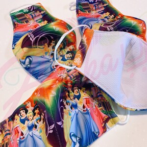 May include: Four colourful face masks featuring a variety of Disney princesses. The masks are made of a soft, breathable fabric and have a white inner lining.