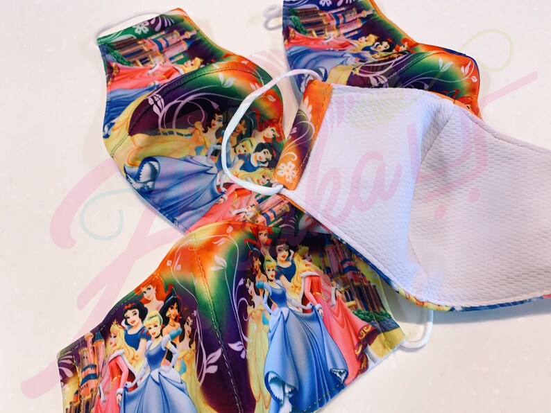 May include: Four colourful face masks featuring a variety of Disney princesses. The masks are made of a soft, breathable fabric and have a white inner lining.