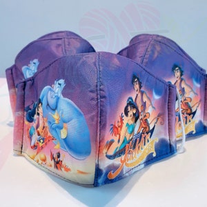 May include: Three purple face masks featuring a printed image of Aladdin, Jasmine, Abu, and Genie from the Disney film Aladdin. The masks have white elastic ear loops.
