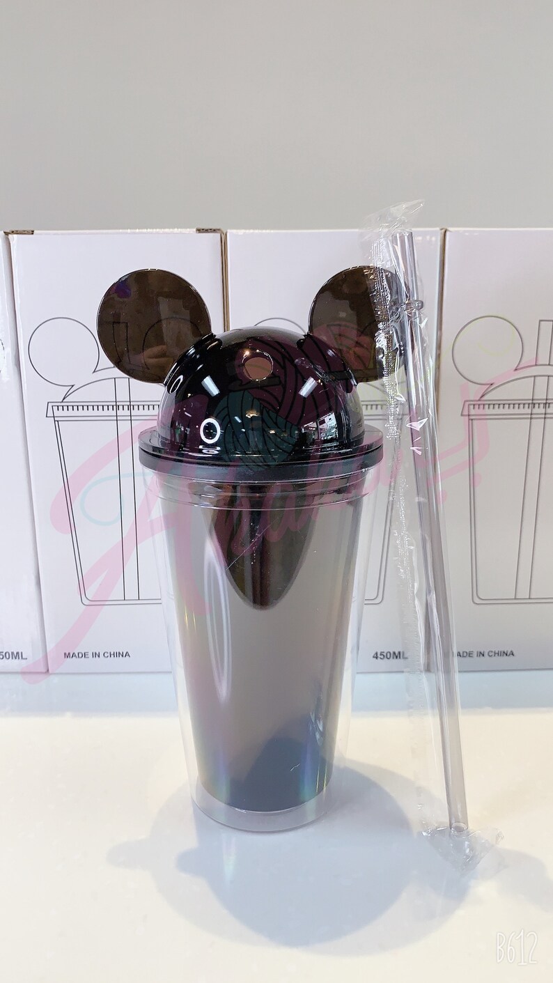 May include: A clear plastic tumbler with a black and white Mickey Mouse design on the lid. The tumbler has a iridescent finish and is 450 ml. The tumbler is packaged with a clear plastic straw.