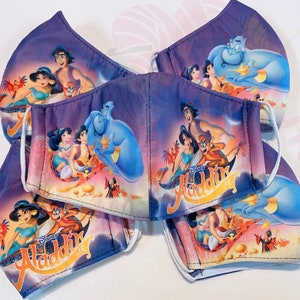 May include: A set of five purple and blue face masks featuring a colourful image of the Disney characters from Aladdin, including Aladdin, Jasmine, Abu, and Genie. The masks have white elastic ear loops.
