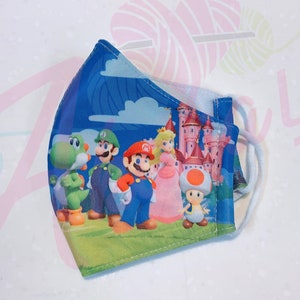 May include: A blue face mask with a colorful print of Mario, Luigi, Peach, Yoshi, and Toad. The characters are standing in front of a pink castle.