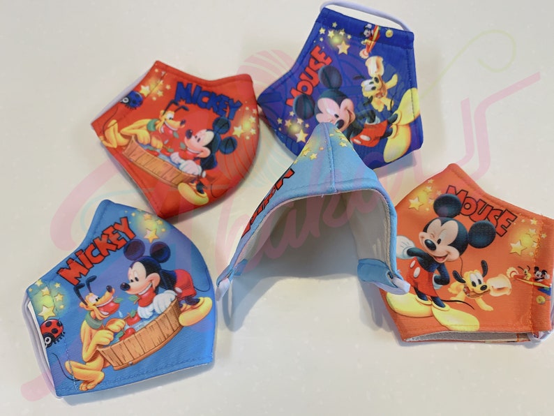 K&ouml;nnte beinhalten: Vier farbenfrohe Gesichtsmasken mit Mickey Mouse und Pluto. Die Masken sind aus Stoff und haben elastische Ohrschlaufen. Die Masken sind mit verschiedenen Designs bedruckt, darunter Mickey Mouse und Pluto in einer Badewanne, Mickey Mouse und Pluto spielen mit Sternen, Mickey Mouse und Pluto spielen mit einem Ball und Mickey Mouse und Pluto spielen mit einem Flugzeug.