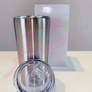 Puede incluir: Un vaso de acero inoxidable con una tapa transparente. El vaso es plateado y tiene un acabado cepillado. La tapa tiene una junta de silicona alrededor del borde.