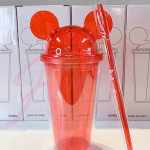 May include: Red plastic tumbler with Mickey Mouse ears and a straw. The tumbler is clear with a red lid and has a 450 ml capacity. The tumbler is made in China.