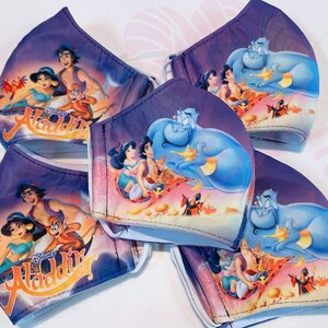 May include: Five purple and blue face masks featuring a Disney Aladdin theme. The masks depict images of Aladdin, Jasmine, Abu, and Genie. The masks are made from a soft, breathable fabric.